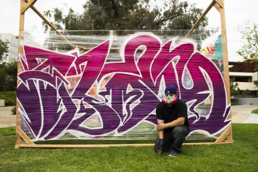 A student poses with graffiti art work at University Centers Graffiti Hill event in May. Graffiti Art Park is planned to become a lasting part of the campus art community. Photo by Claire Frausto.
